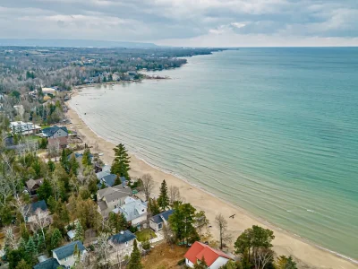 Aerial view of Wasaga Beach coastline lined with residential homes and forested areas stretching along Nottawasaga Bay.