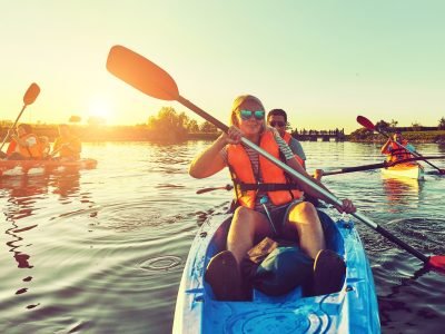 Group of people kayaking on calm water at sunset near Wasaga Beach, wearing life jackets and enjoying outdoor recreation.